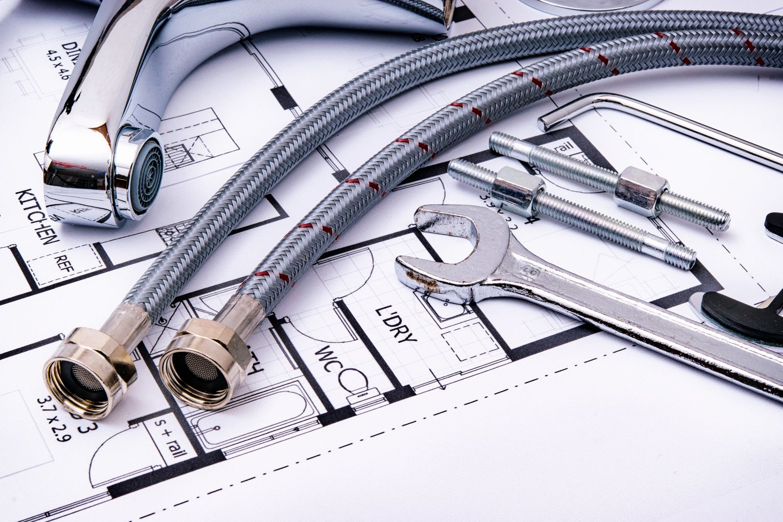 Plumbing tools and faucet on a blueprint